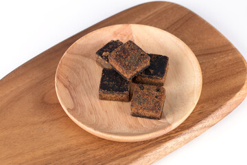 Black cubes brown sugar on a plate, plate on a cutting board
