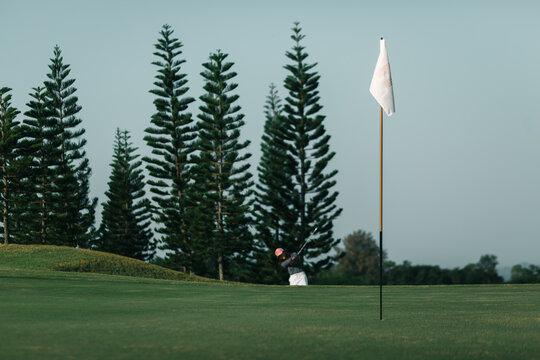 Flagpole placed at the golf hole on putting Green and golfer's as a background.