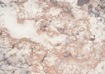 Pale brown marble with white splashes, close-up of polished natural stone surface.