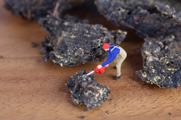 Miniature worker with chainsaw cutting black brick tea