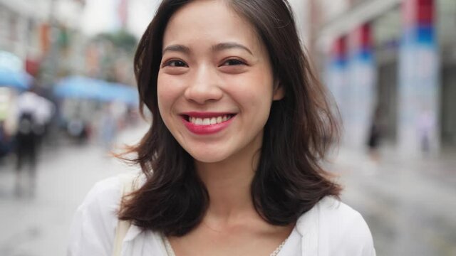 Charming young asian lady looking at camera smile in the urban city of Chengdu close up 4k slow motion of beautiful Chinese woman portrait in the street