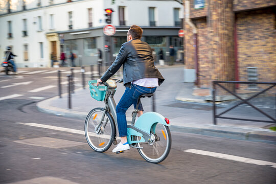 Cyclist on a rented bike with an electric motor for city travel rides down a street in old Paris