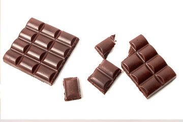 Broken bar of dark porous chocolate, pieces of chocolate on white isolated background