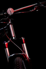 Mountain bike with shock absorbers in red lighting on black background