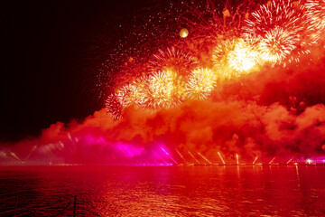Festive colorful fireworks and illumination in dark sky with beautiful reflection in water. Holiday SCARLET SAILS