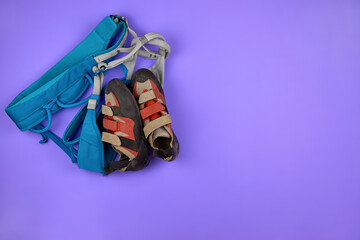 Climbing Shoe and Climbing harnesses, copy space. Climbing equipment on a purple background. The...