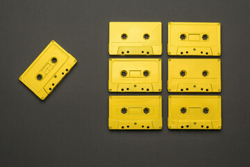 A set of yellow cassettes for a tape recorder on a dark gray background. Flat lay.