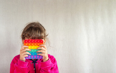 Cute faceless child playing with the Pop It fidget. Push pop bubble flexible fidget sensory toy provide discharge and are good for the development of kid. Selective focus on toy.