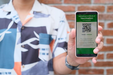 Close up hand's asian man showing smartphone display on app mobile vaccinated COVID-19 or coronavirus certificate. Digital health certificate is required for international travel. selected focus.