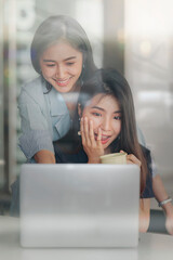 Young asian lesbian couple using laptop together at home.