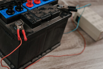 Closeup of car accumulator with battery jumper charging at home