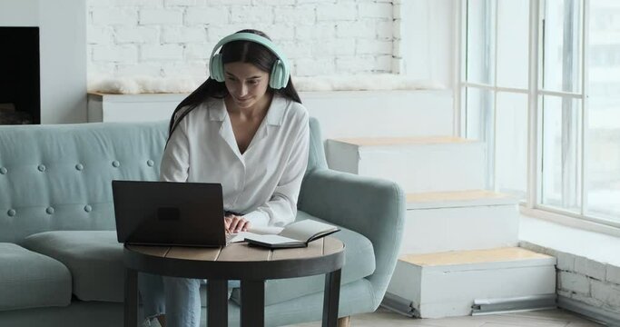 Serious young Caucasian woman speaking by video call and looking at laptop. Distance language learning with student and tutor concept. Stay home and zoom education concept.