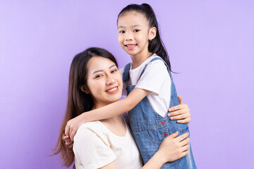 Portrait of Asian mother and daughter on purple background