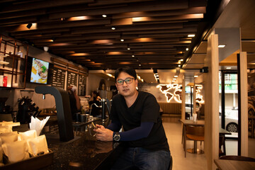 Portrait a man sitting infront of coffee bar in cafe