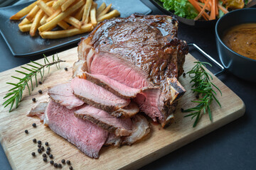 Close-up view of Grilled marble Rib eye steak beef for steak on wooden plate with salad and French fries.