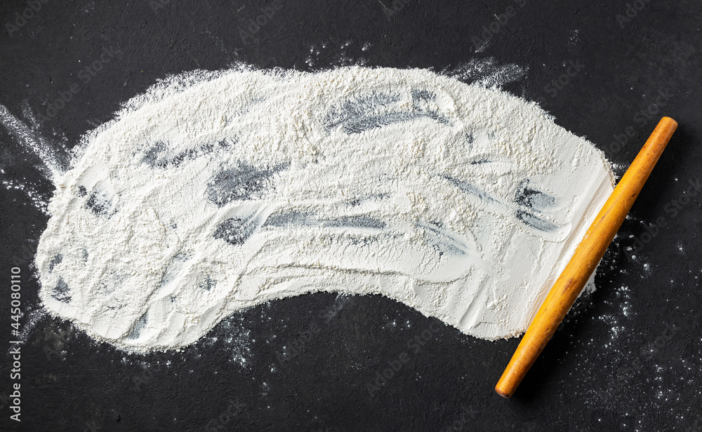 Poster abstract baking background with flour and rolling pin on black table top view