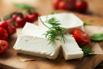 Feta cheese with dill and cherry tomatoes on cutting board close up