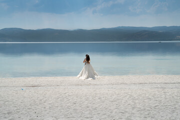 Fototapeta na wymiar On the special white sands of the world-famous Salda lake, the bride and groom in white wedding dresses have their photos taken before their honeymoon.