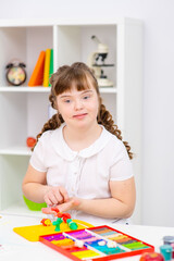A girl with the syndrome at the table are engaged in creativity.