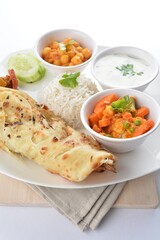Indian baked roti prata canai with curry vegetables, yogurt sauce, pea bean and steamed white rice in white background asian vegan halal menu