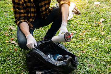 Man's hands pick up plastic bottles, put garbage in black garbage bags to clean up at parks, avoid pollution, be friendly to the environment and ecosystem