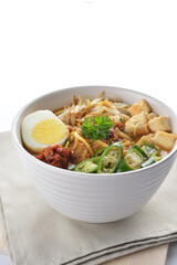 Malay mee rebus noodle with boiled egg, tofu, green chilli, sambal chilli sauce and hot thick curry gravy soup bowl in white background asian halal menu