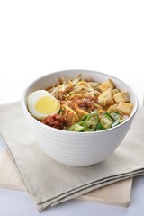 Malay mee rebus noodle with boiled egg, tofu, green chilli, sambal chilli sauce and hot thick curry gravy soup bowl in white background asian halal menu