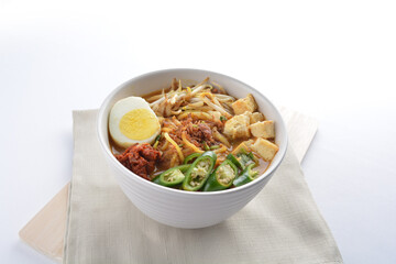 Malay mee rebus noodle with boiled egg, tofu, green chilli, sambal chilli sauce and hot thick curry gravy soup bowl in white background asian halal menu