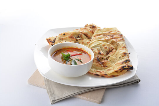 indian roti prata canai 2 pieces with spicy curry chicken gravy soup in bowl in white background asian halal menu