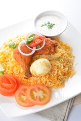 traditional Indian fragrant yellow nasi biryani rice with tandoori chicken, poached egg and yogurt sauce in white background asian halal menu