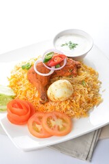 traditional Indian fragrant yellow nasi biryani rice with tandoori chicken, poached egg and yogurt sauce in white background asian halal menu