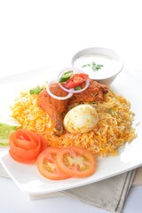 traditional Indian fragrant yellow nasi biryani rice with tandoori chicken, poached egg and yogurt sauce in white background asian halal menu
