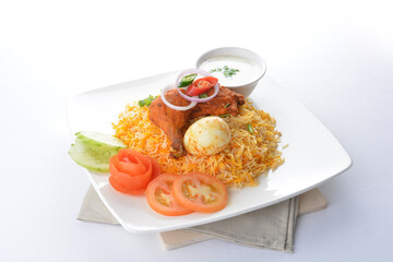 traditional Indian fragrant yellow nasi biryani rice with tandoori chicken, poached egg and yogurt sauce in white background asian halal menu