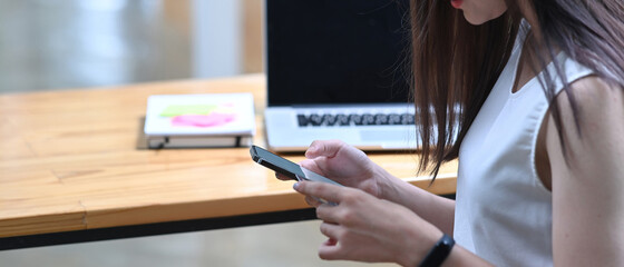 Cropped shot of casual woman using smart phone at office.