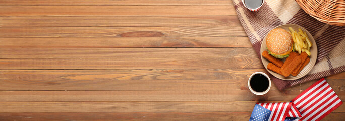 Traditional American food with picnic basket and flags on wooden background with space for text