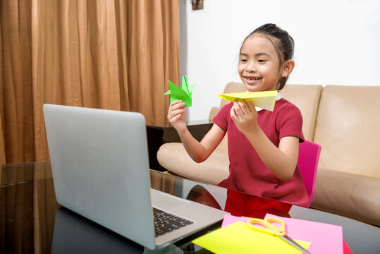 Asian little girl with laptop attending to online school class at home