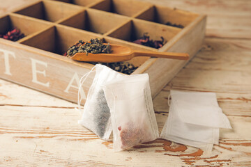 Fototapeta na wymiar Tea bags and box with dry leaves on light wooden background
