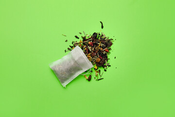 Tea bag with dry leaves on color background