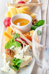 A set of cheeses, different varieties with grapes and honey. Breadsticks.