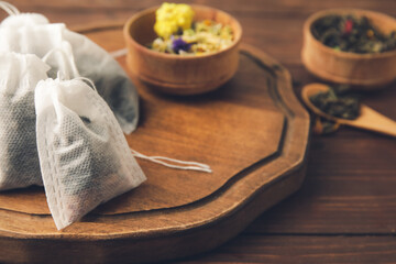 Fototapeta premium Tea bags and bowls with dry leaves on wooden background