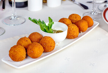 Meat budo stuffed with cheese and garlic. Deep-fried balls, next to wine glasses and wine.