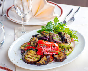 A plate of roast vegetables, a glass of wine beside it.
