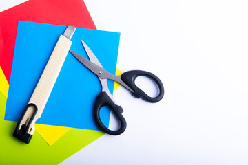 Stack of colored paper with scissors and cutter