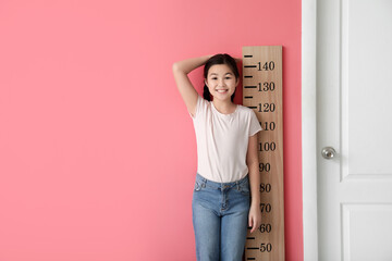 Little girl measuring height near color wall - obrazy, fototapety, plakaty