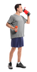 Sporty male coach with dumbbell and water on white background