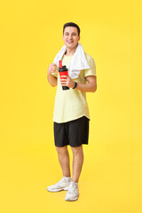 Sporty male coach with bottle of water on color background