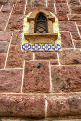 Selective focus of old rustic stone wall with small window and ironwork
