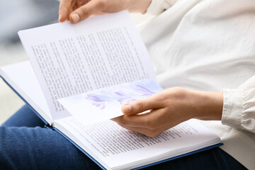 Woman with book and bookmark at home, closeup