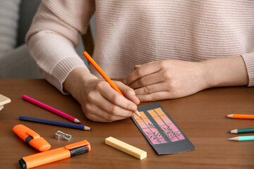 Woman coloring bookmark at table, closeup