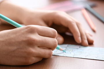 Woman coloring bookmark at table, closeup